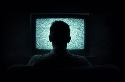 Silhouette watching television in dark room representing AI companion viewing