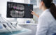 Dentist using AI software to analyse dental X-rays on a screen in a modern clinic setting.