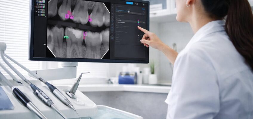 Dentist using AI software to analyse dental X-rays on a screen in a modern clinic setting.