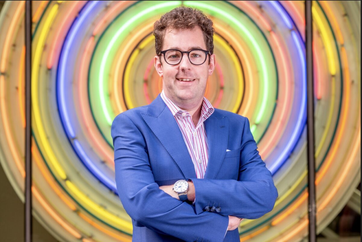 Josh Hough founder of CareLineLive standing in front of colorful circular light installation