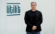 Nikolajus Gavrilinas, co-founder and CEO of LITILIT, standing beside the company's logo