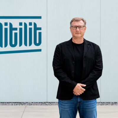 Nikolajus Gavrilinas, co-founder and CEO of LITILIT, standing beside the company's logo
