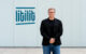 Nikolajus Gavrilinas, co-founder and CEO of LITILIT, standing beside the company's logo