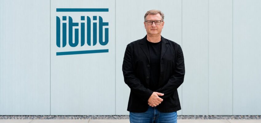 Nikolajus Gavrilinas, co-founder and CEO of LITILIT, standing beside the company's logo